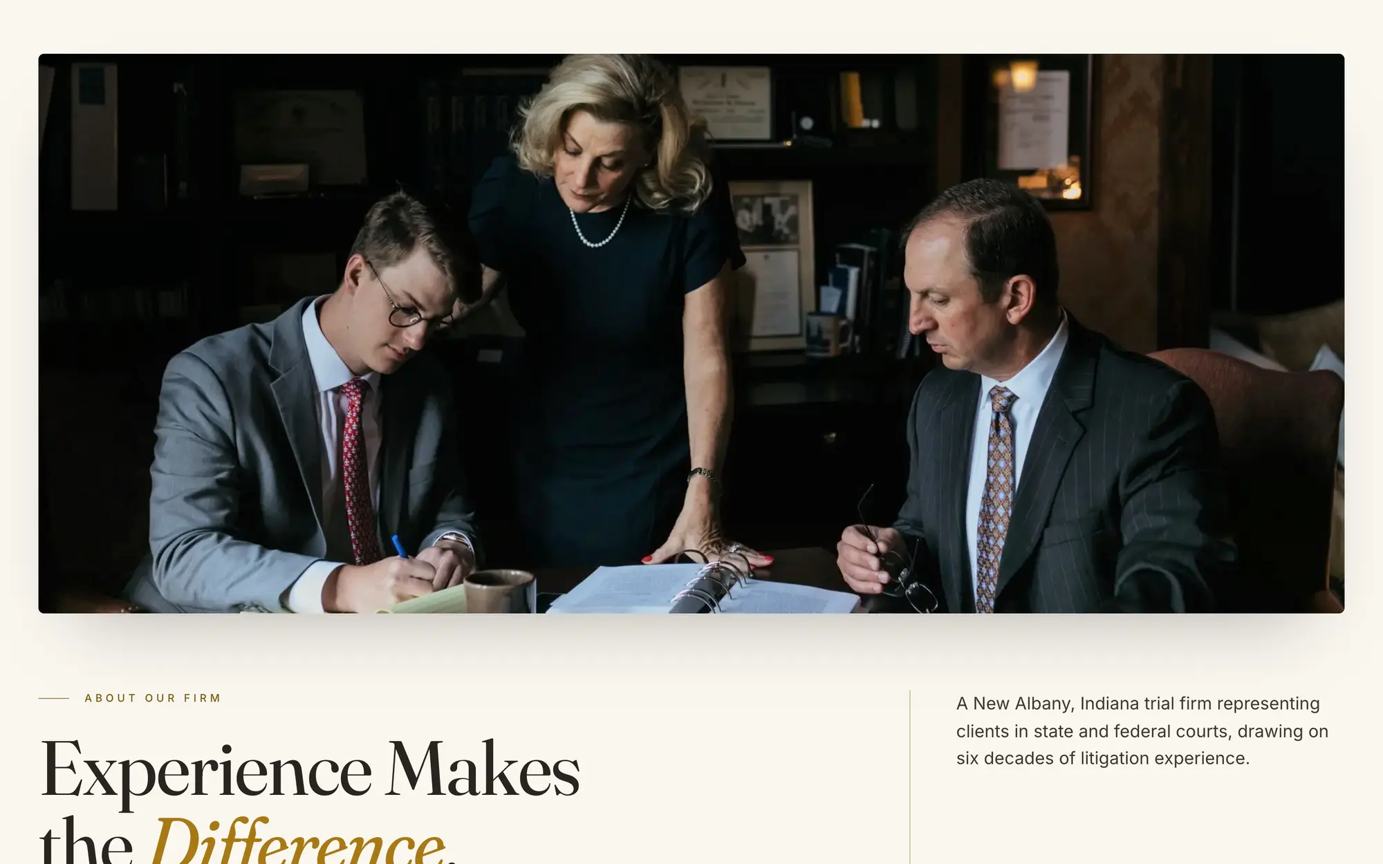 Desktop Our Firm page opening on a full-width photo of the attorneys reviewing case files together.